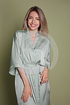 Pretty young woman in beautiful light green silk robe on olive background