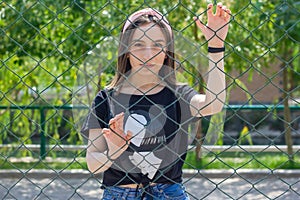 Pretty young woman behind fence, young woman in a park