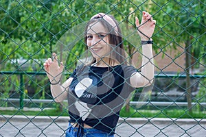 Pretty young woman behind fence, young woman in a park