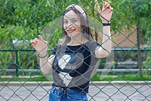 Pretty young woman behind fence, young woman in a park