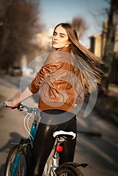 Pretty young woman with bicycle in a city road