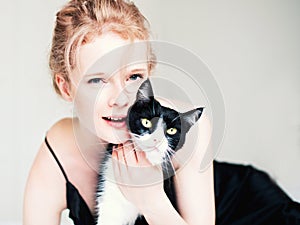 Pretty young woman with black cat in blanket