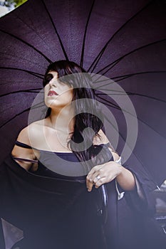 Pretty young woman with black umbrella, under autumn rain in a p
