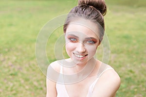 Pretty young woman with bright make up. Outdoor green portrait