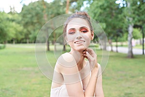 Pretty young woman with bright make up. Outdoor green portrait