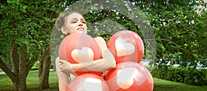Pretty young woman with bright make up. Outdoor green portrait. Red balloons