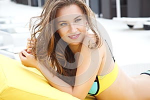 Pretty young woman in bright summer bikini on a beach lounger