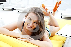 Pretty young woman in bright summer bikini on a beach lounger