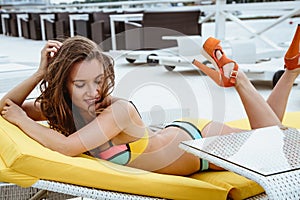 Pretty young woman in bright summer bikini on a beach lounger