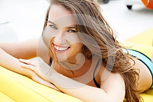 Pretty young woman in bright summer bikini on a beach lounger