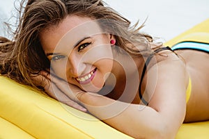 Pretty young woman in bright summer bikini on a beach lounger