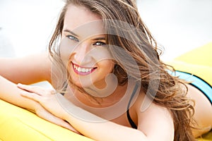 Pretty young woman in bright summer bikini on a beach lounger