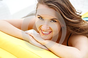 Pretty young woman in bright summer bikini on a beach lounger