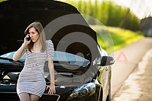 Pretty, young woman calling the roadside service/assistance