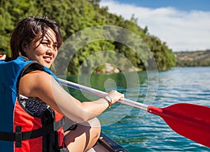 Pretty, young woman on a canoe on a lake, paddling