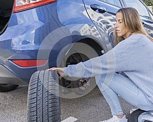 Pretty young woman changing wheel