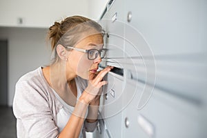 Pretty, young woman checking her mailbox