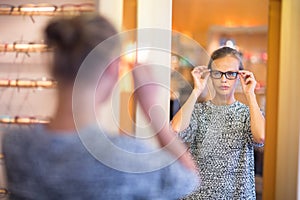 Pretty, young woman choosing new glasses frames