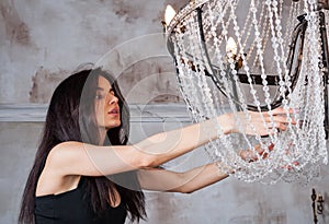 Pretty young woman choosing the right chandelier for her appartment in a vintage home.