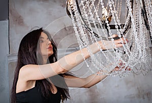 Pretty young woman choosing the right chandelier for her appartment in a vintage home.