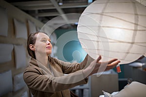 Pretty, young woman choosing the right lamp