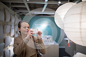 Pretty, young woman choosing the right lamp