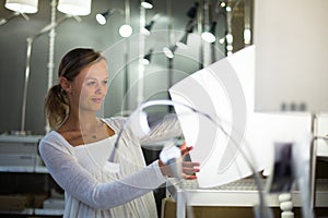 Pretty, young woman choosing the right light for her apartment