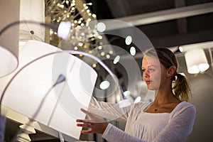 Pretty, young woman choosing the right light for her apartment i