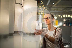 Pretty, young woman choosing the right light for her appartment