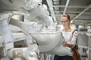 Pretty, young woman choosing the right pillow