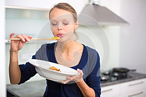 Pretty, young woman cooking a diner in a modern kitchen