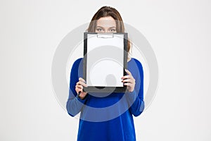 Pretty young woman covered her face with blank clipboard