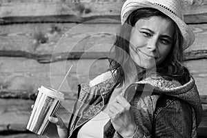 Pretty young woman in cowboy hat. Black and white portrait of attractive girl in jeans jacket on wooden fence background.