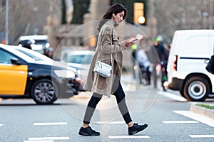 Pretty young woman crossing the street while listen to music with the wireless earphones