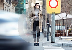 Pretty young woman crossing the street while listen to music with the wireless earphones