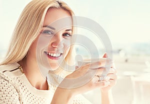 Pretty young woman with cup of coffee in sunny restaraunt