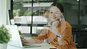 Pretty young woman customer holding credit card and using laptop making purchase in online store or payment online. Slow