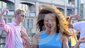 Pretty young woman dancing and waving hair from side to side, enjoying party with friends. Party on the rooftop