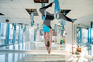 Pretty young woman doing fly yoga stretching exercises  in fitness training  gym. Health, fly yoga concept