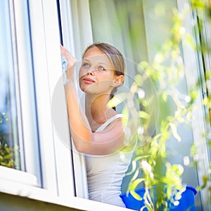 Pretty, young woman doing house work - washing windows