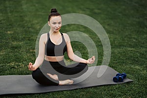 Pretty young woman doing yoga exercise in the park