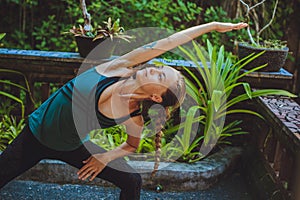 Pretty young woman doing yoga outside in natural environment