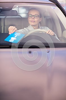 Pretty, young woman driving her new car - putting the necessary parking clock behind the windshield photo