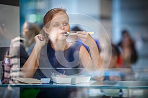 Pretty, young woman eating sushi in a restaurant