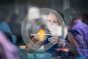 Pretty, young woman eating sushi in a restaurant