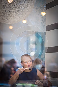 Pretty, young woman eating sushi in a restaurant