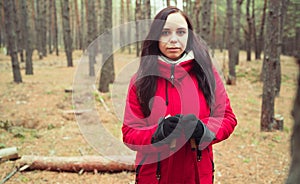 A pretty young woman is engaged in the nordic walking in woods.
