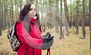 A pretty young woman is engaged in the nordic walking in woods.