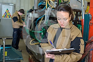 Pretty young woman engineer checking for malfunctions at factory