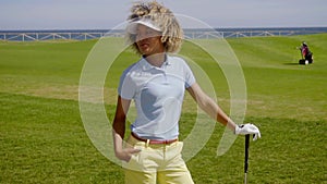 Pretty young woman enjoying sun while playing golf